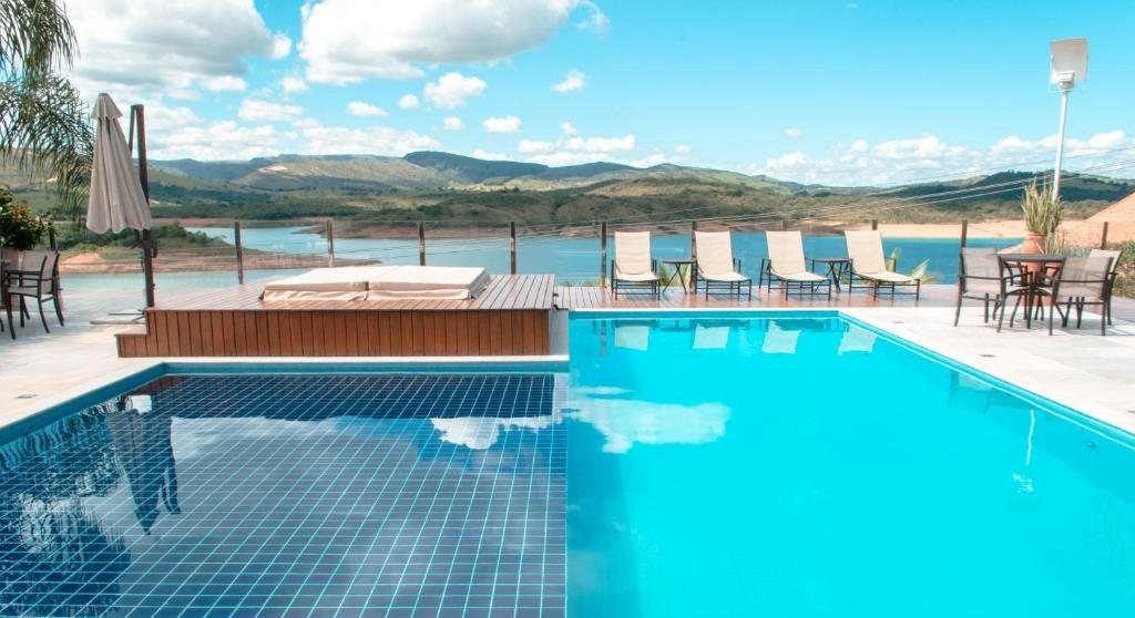 Piscina e espreguiçadeiras no deck, diante da Represa de Furnas e das montanhas